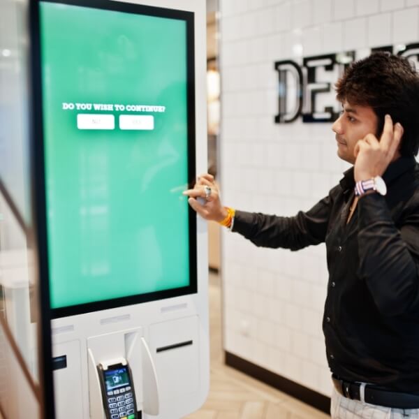 Mann bedient ein digitales Self-Service-Terminal mit Touchscreen